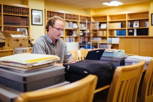 A man doing research in the Brechner library surrounded by boxes of archival materials.