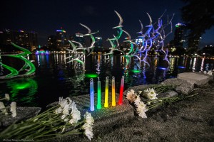 Impromptu memorial for Pulse Nightclub Tragedy victims with rainbow colored glow sticks and a sculpture of bird in the background