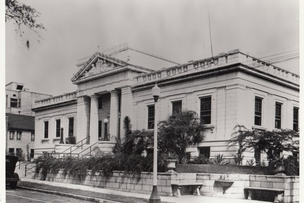 Historic sepia-tone image of the Albertson Public LIbrary, a classic style building with a palm tree in front