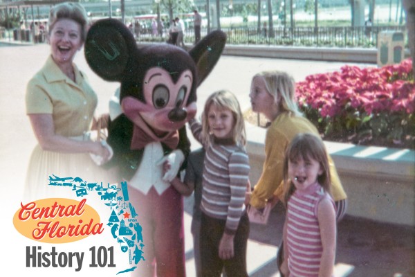 An adult female and four children greet Mickey Mouse in the early days of Walt Disney World