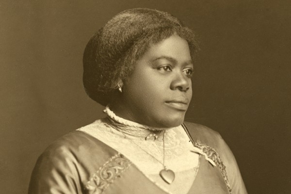 Sepia-toned portrait of Mary McLeod Bethune wearing a high collared dress with a heart necklace