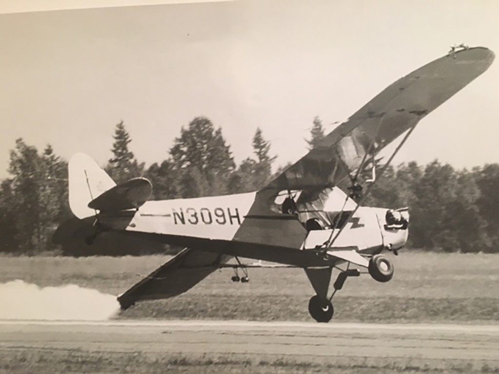 Airplane flies close the ground with flour billowing from wingtip.