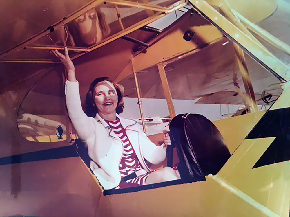 Grace the Ace seated in a yellow biplane 