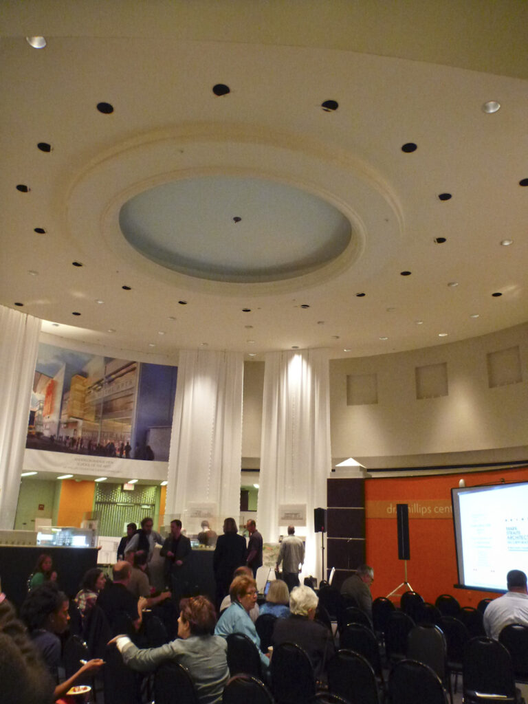 Interior of the round building from 2014 shows people in chairs in the bottom third of the photo and the circular ceiling.