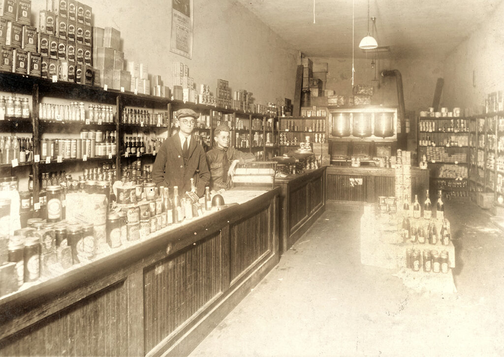 A male adult and a young boy behind the counter in an early 20th century dry goods store in Orlando
