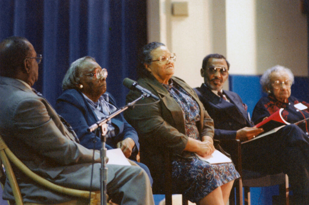 Altermese Bentley, sitting in a chair alongside three other people. She sits second from left, behind a microphone at the 2001 opening of the school that bears her name.

Credit:
Museum of Seminole County History